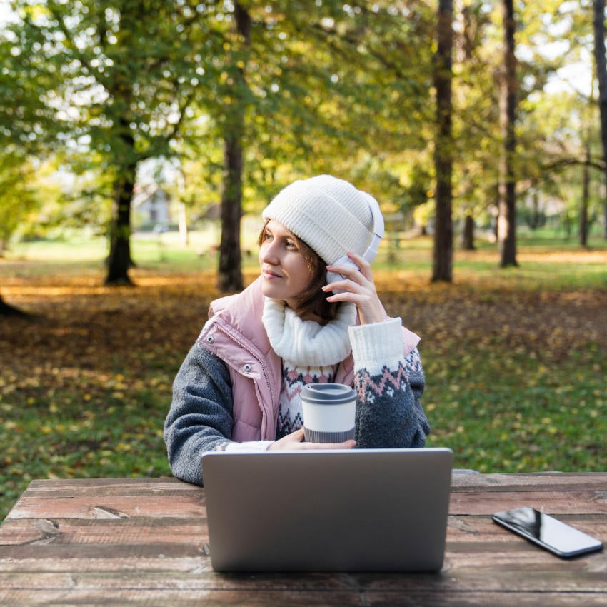 Freelancerin arbeitet im herbstlichen Wald an ihrem Laptop