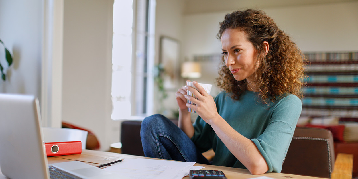 Frau mit Kaffeetasse vor Laptop