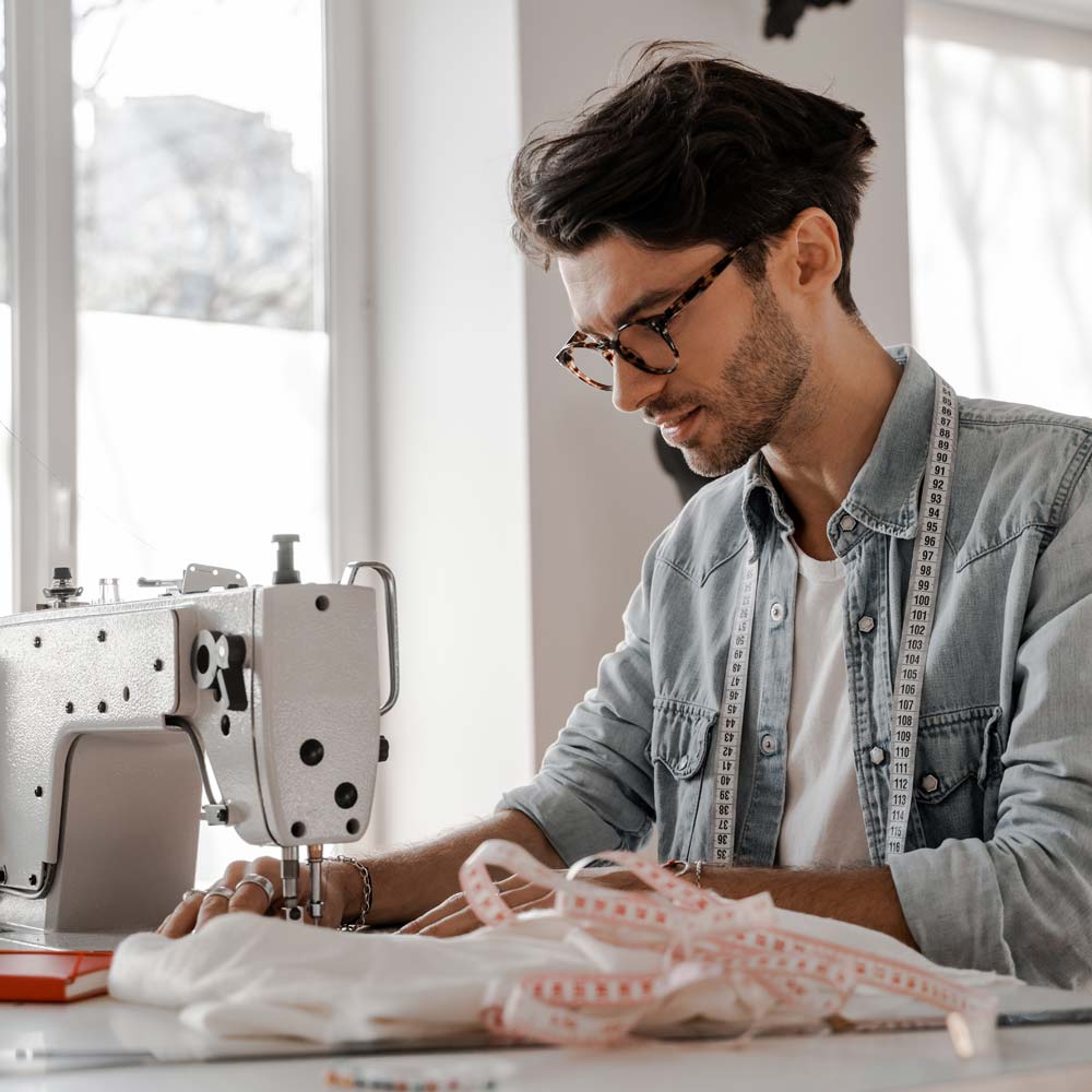 Young man sews at a sewing machine