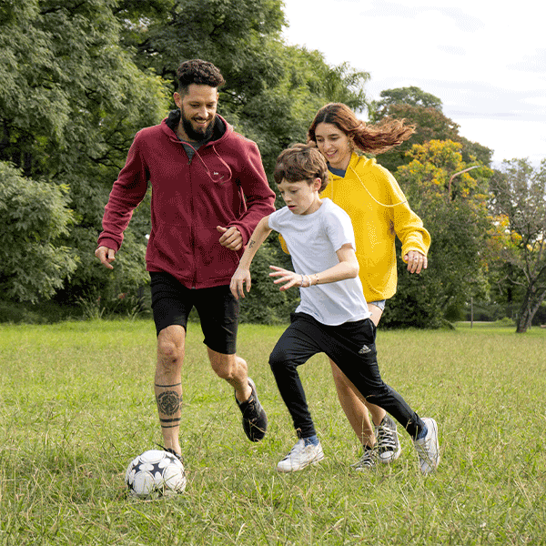 Father and children playing soccer at the park