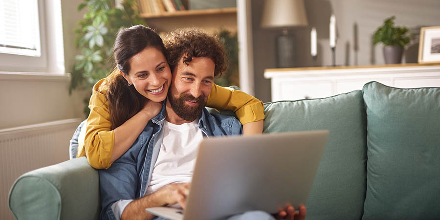 couple sitting on the couch looking into a laptop