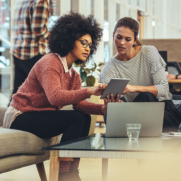 two woman talking about something on a tablet