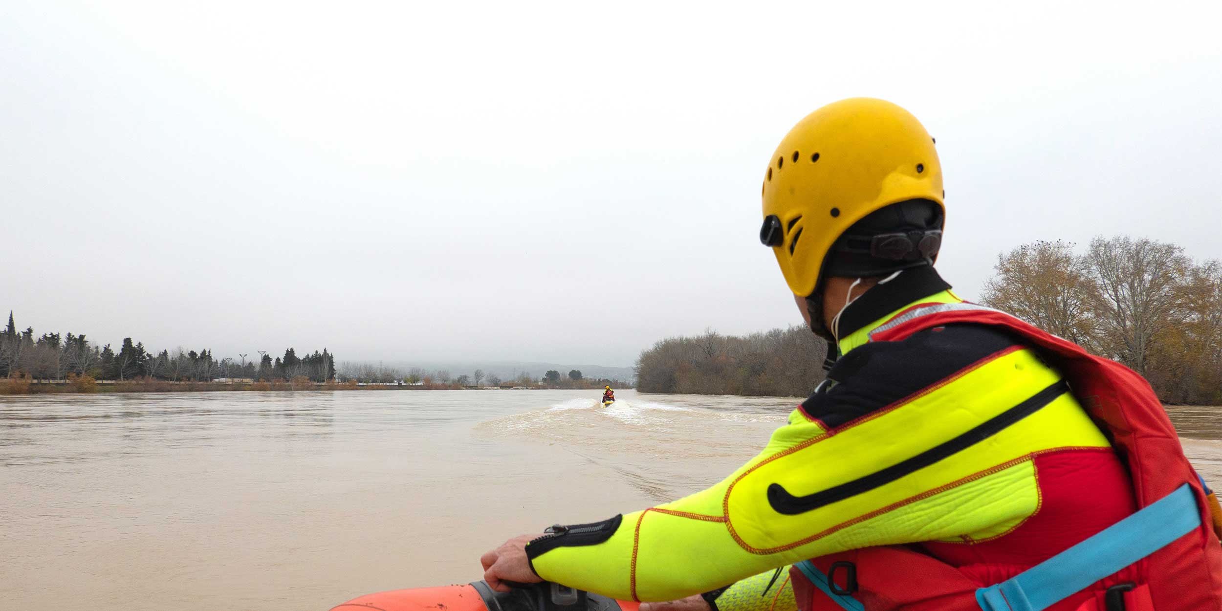 rescuer watches the river during a flood while riding in a boat