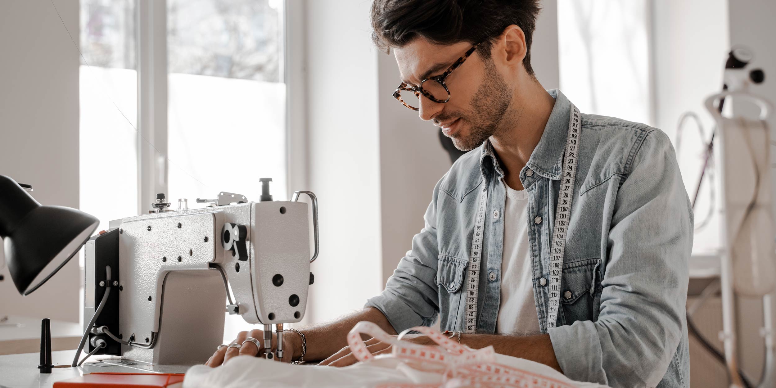 Young man sews at a sewing machine