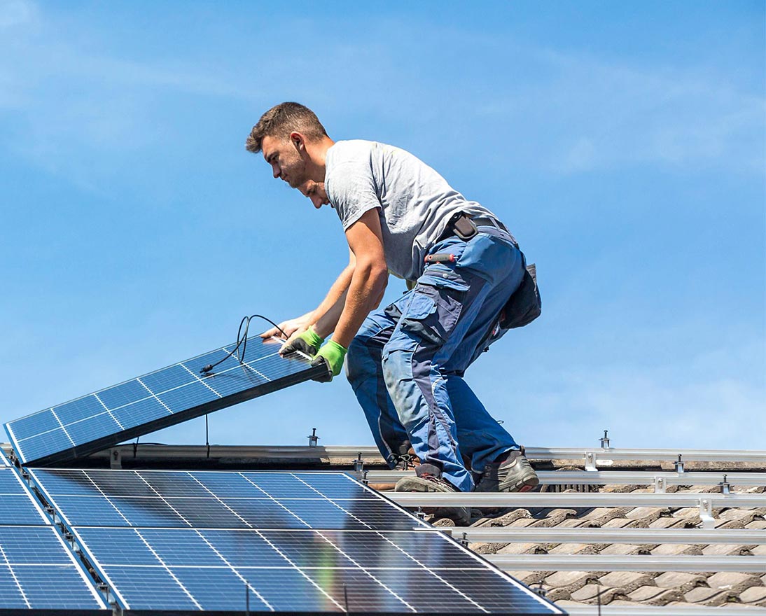 man putting solar panel on roof