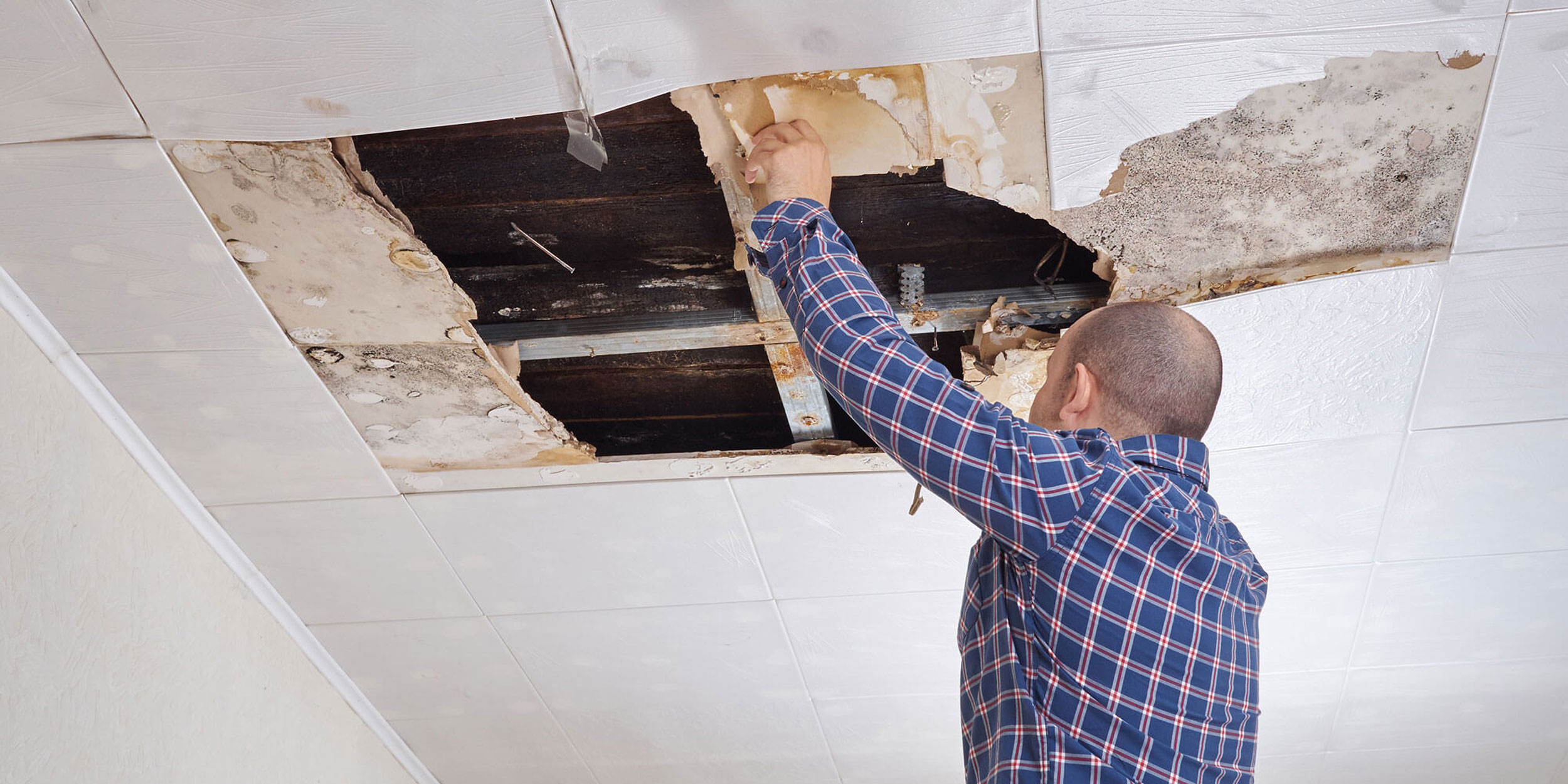 man looking at damaged ceiling