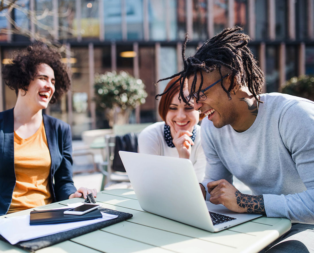 young businesspeople using laptop outdoors