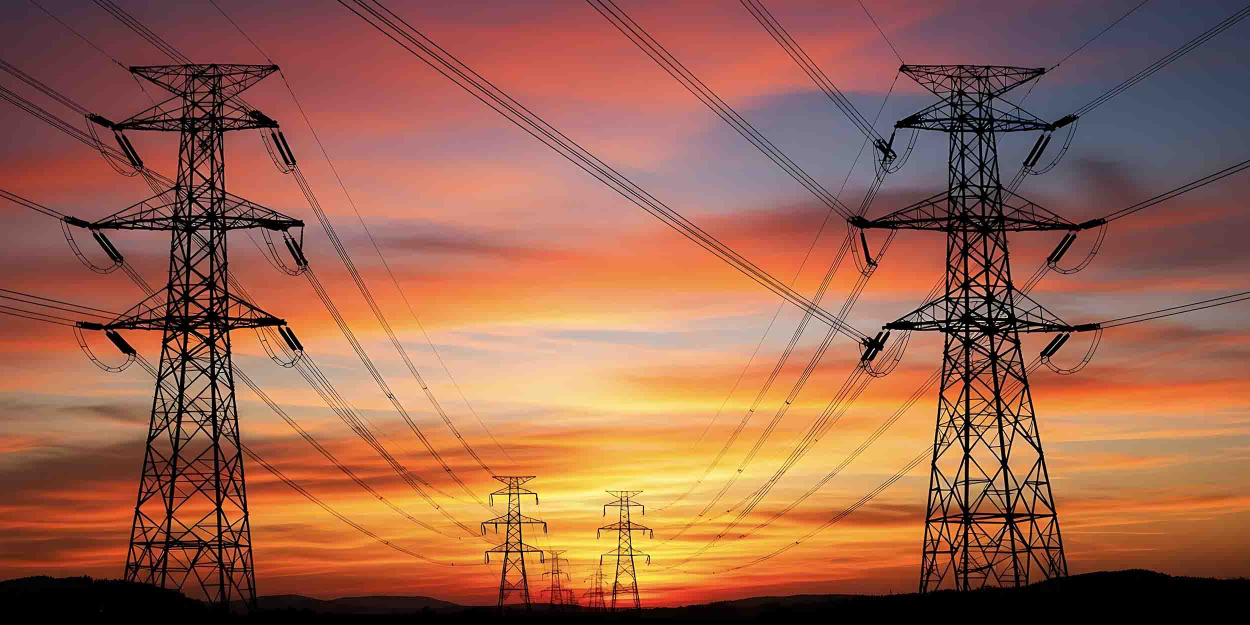 shot of electrical transmission towers silhouetted against a vibrant sunset