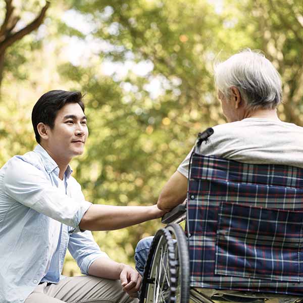 Young man comforts an elderly person in a wheelchair
