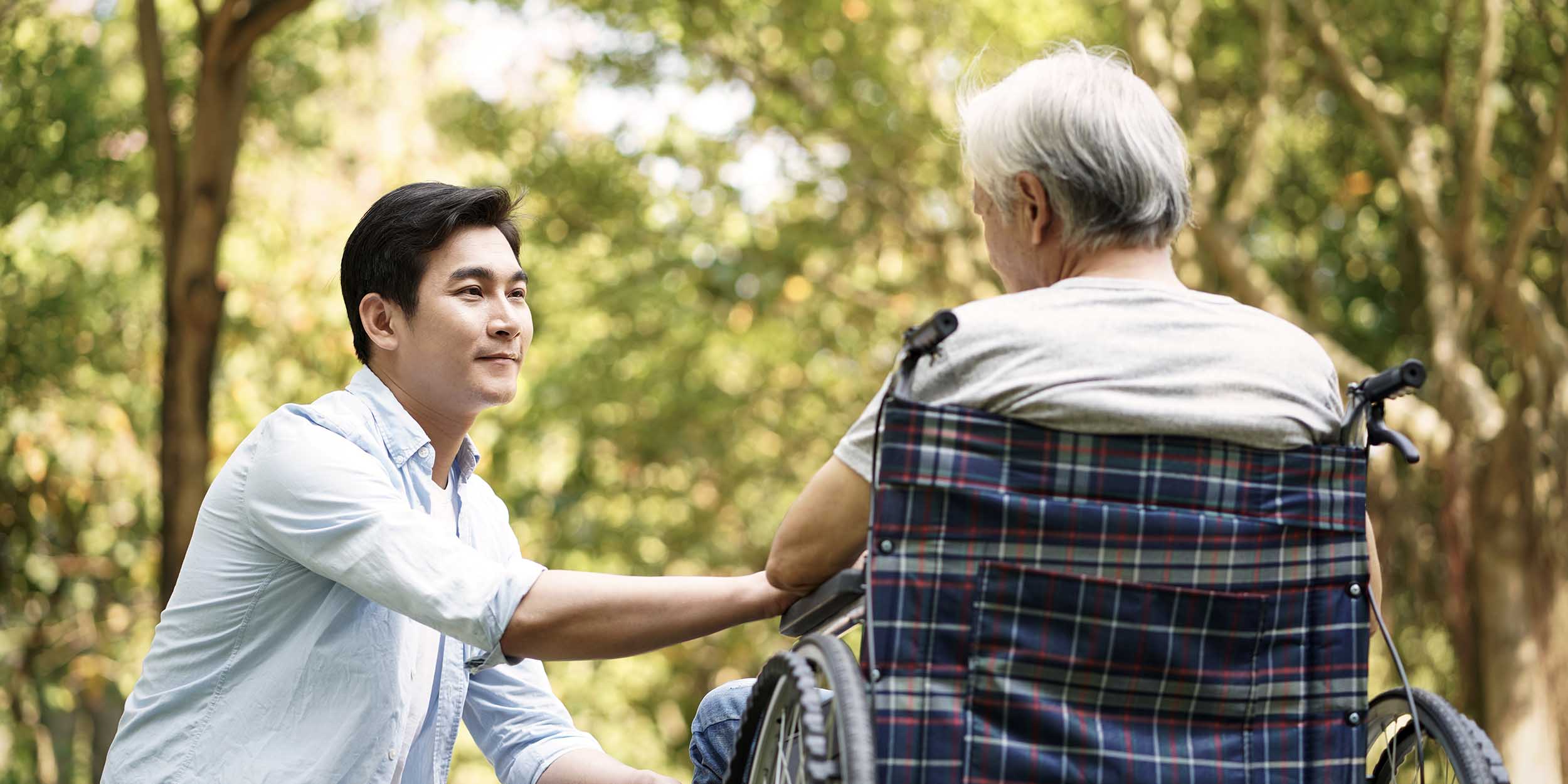 Young man comforts an elderly person in a wheelchair