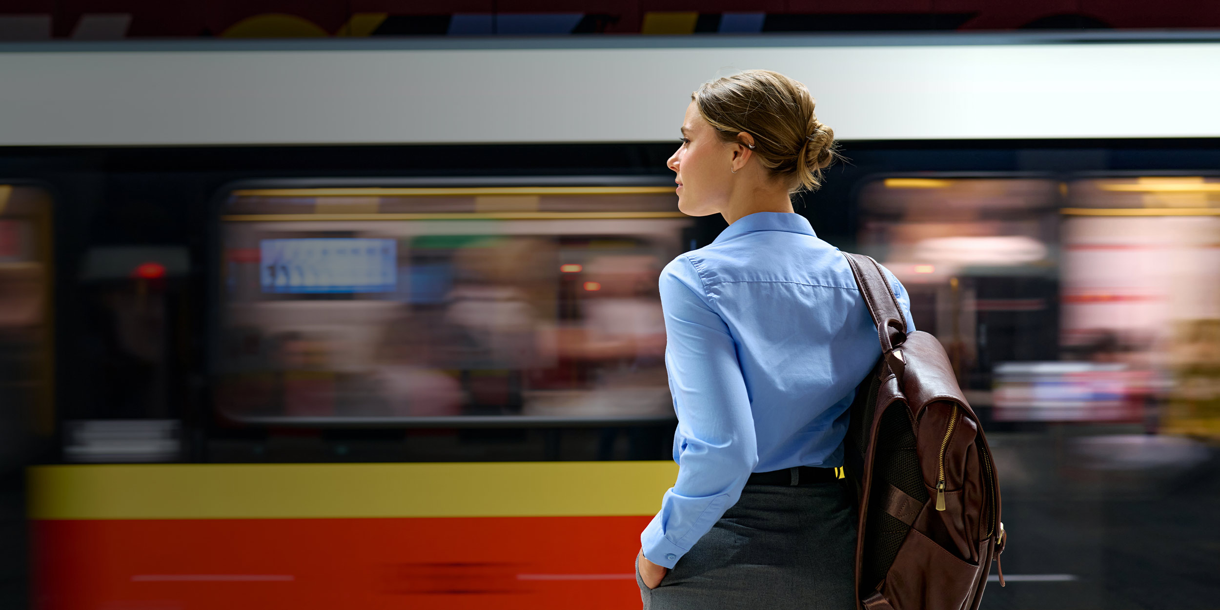Woman standing on a platform at a train station watching a train go by