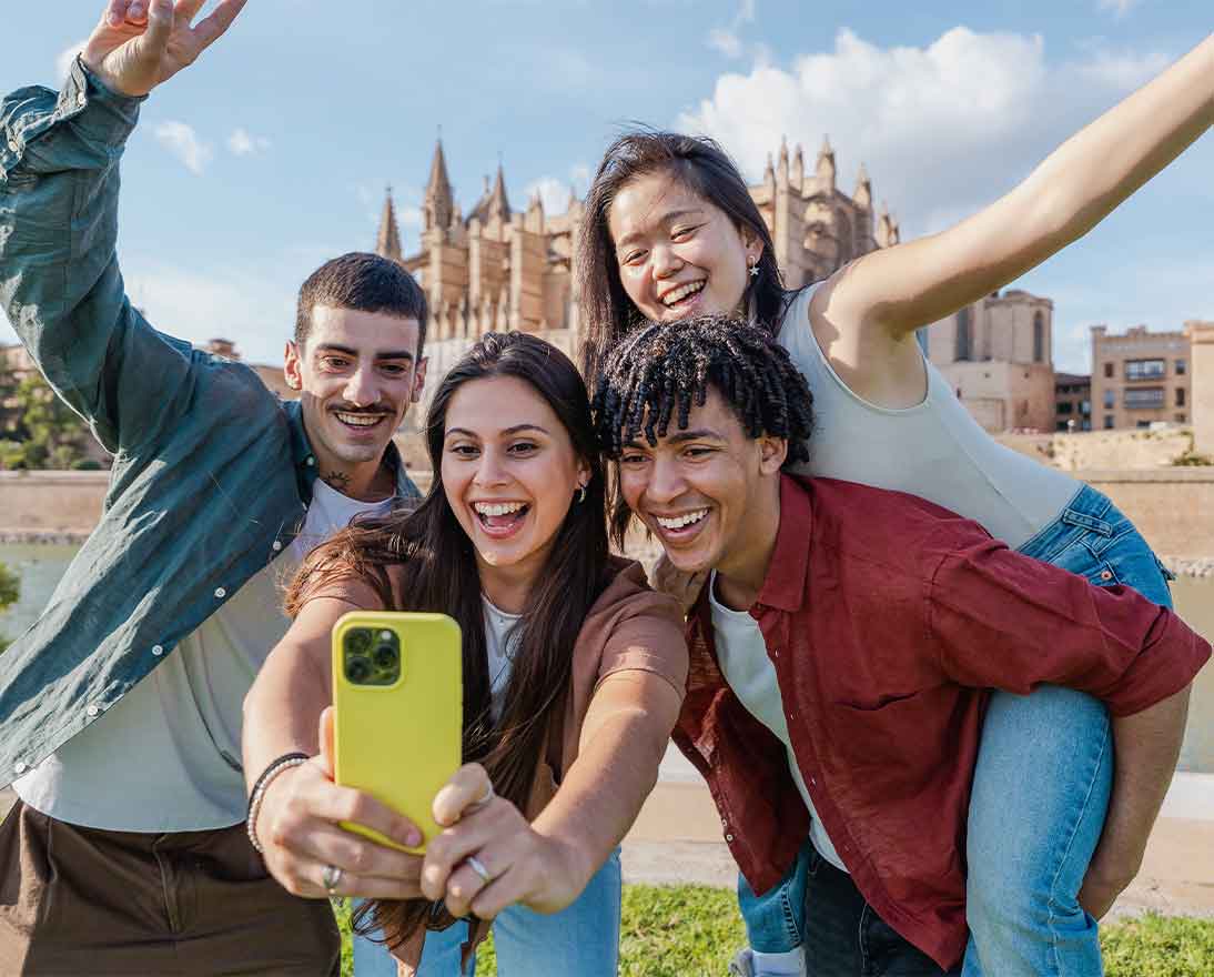 Smiling multiethnic group of young friends taking a fun selfie near a cathedral