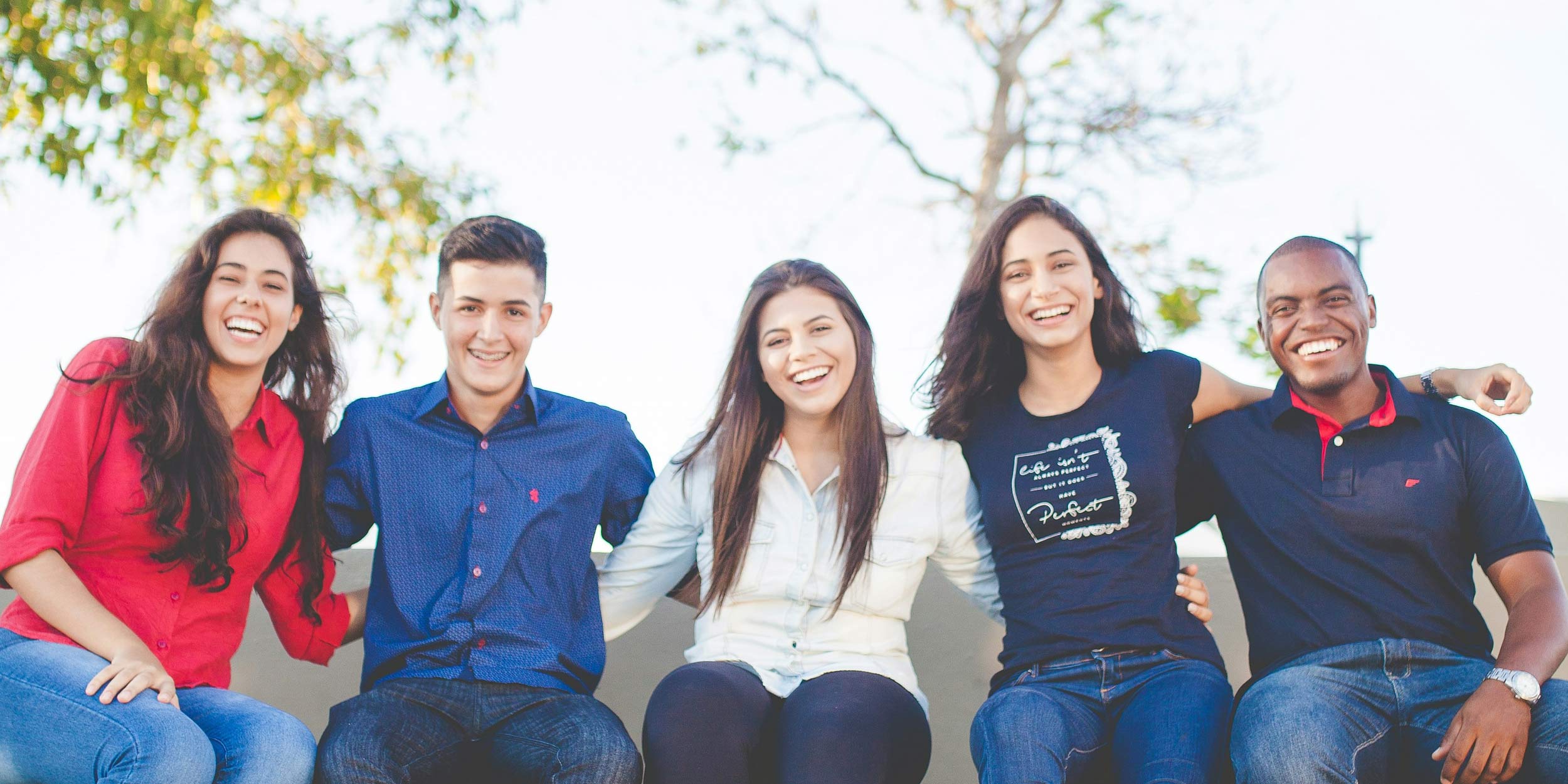 Group of GenZ people sitting together smiling
