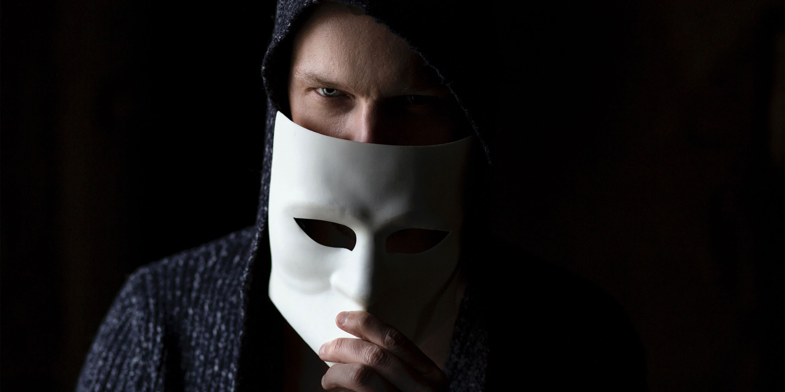 a man hiding his face behind a mask