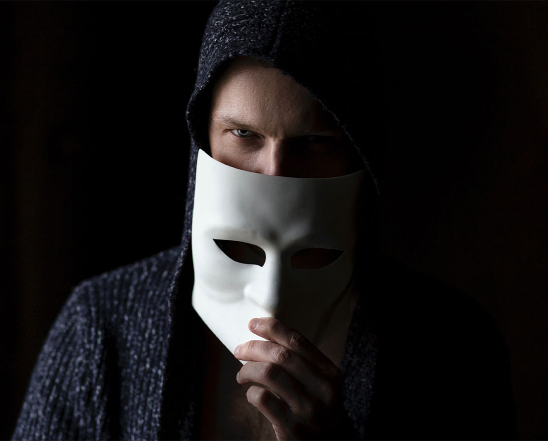 a man hiding his face behind a mask