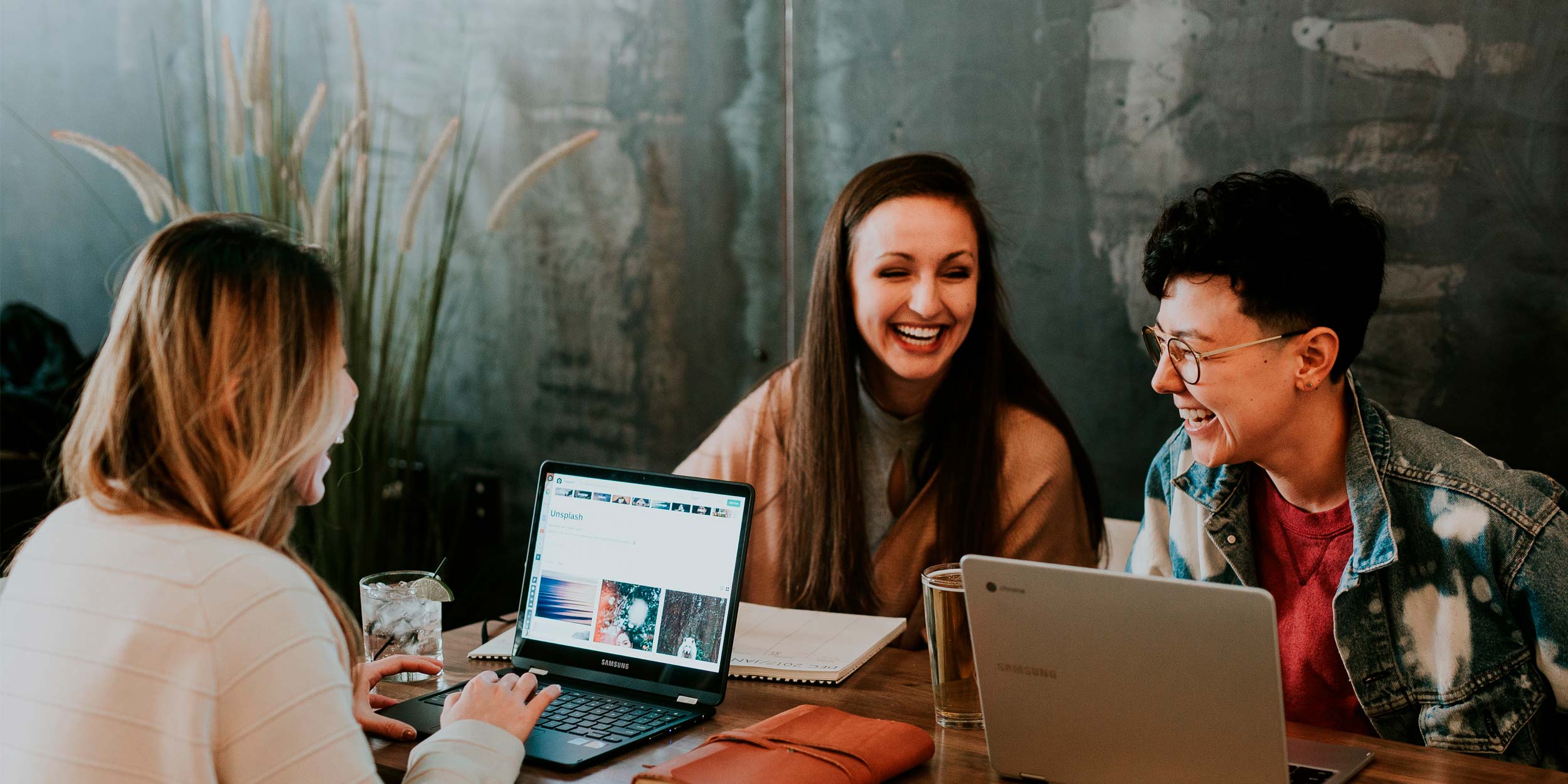 Three people sitting in front of table laughing together