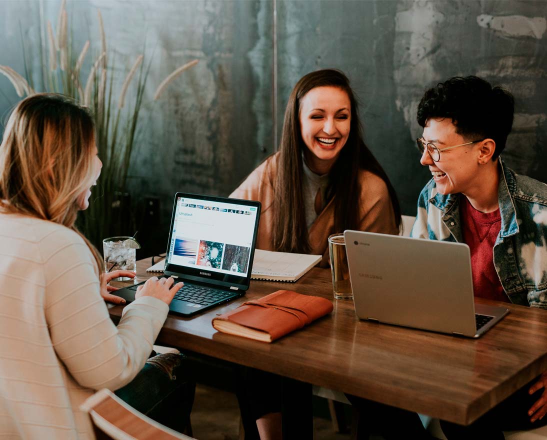 Three people sitting in front of table laughing together