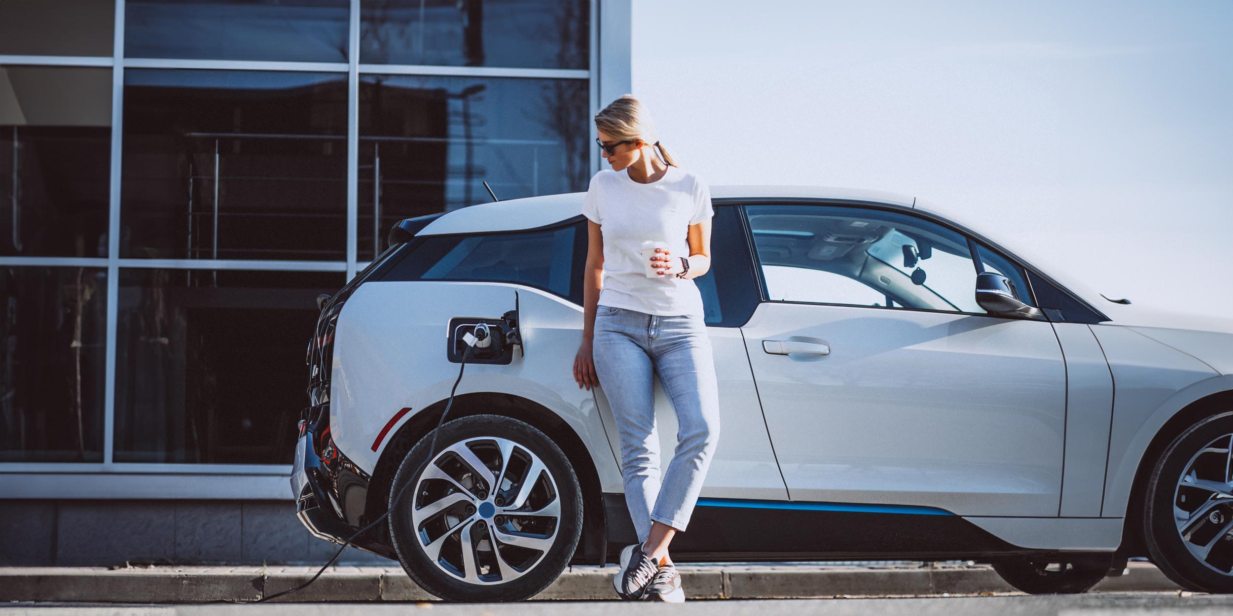 Young woman recharging battery for electric car
