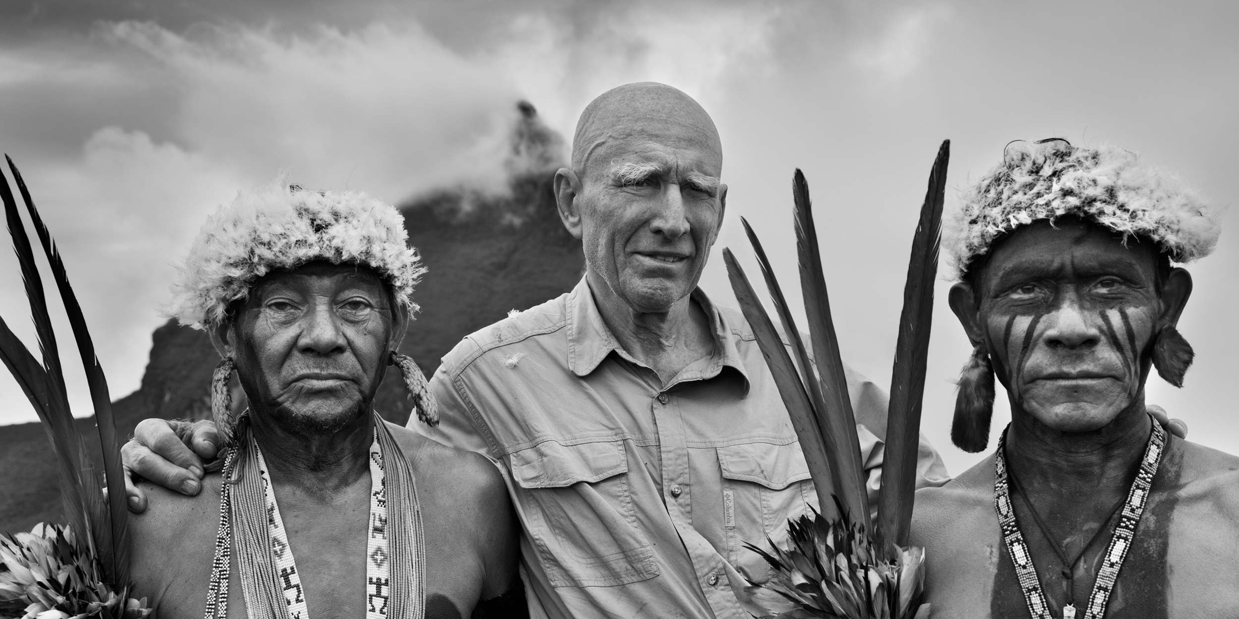 Sebastião Salgado with Yanomami indigenous people in the Amazon in 2014, with Brazil’s highest peak, Pico da Neblina, in the background. © Sebastião Salgado. All rights reserved