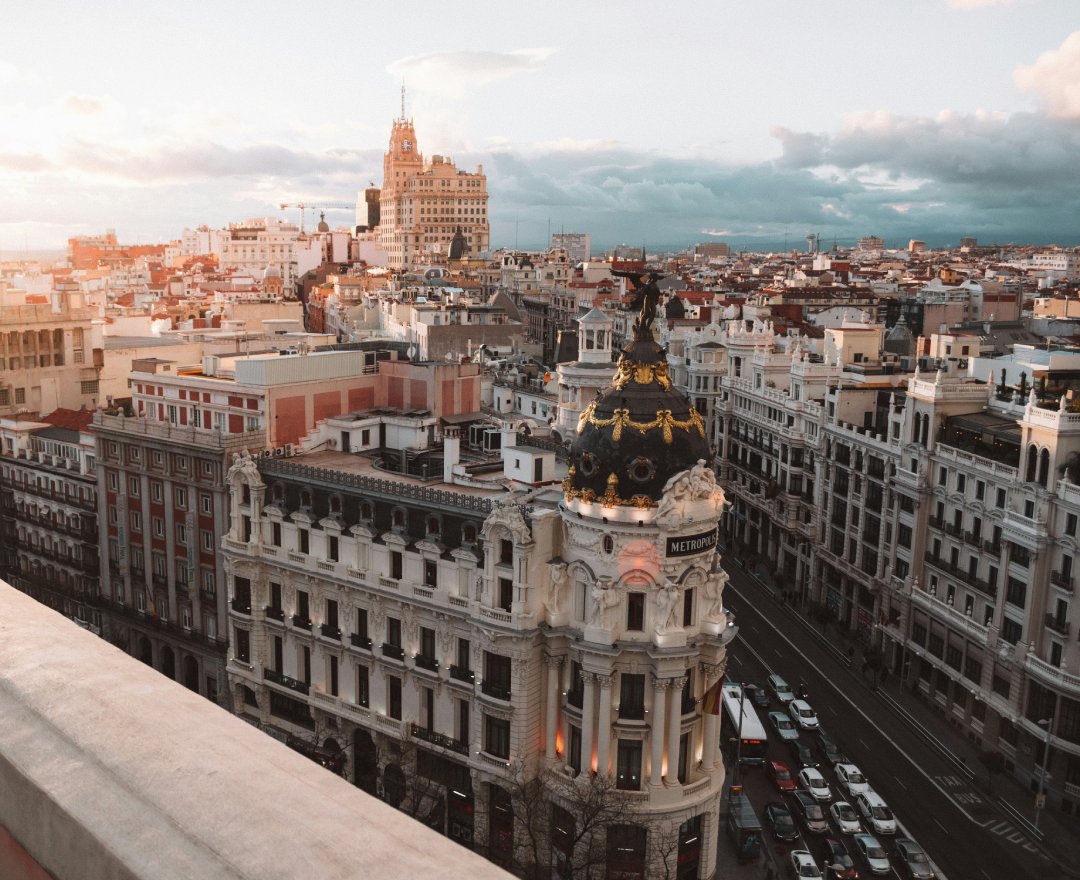Aerial view of Madrid’s Gran Vía at sunset, featuring the iconic Metropolis building.