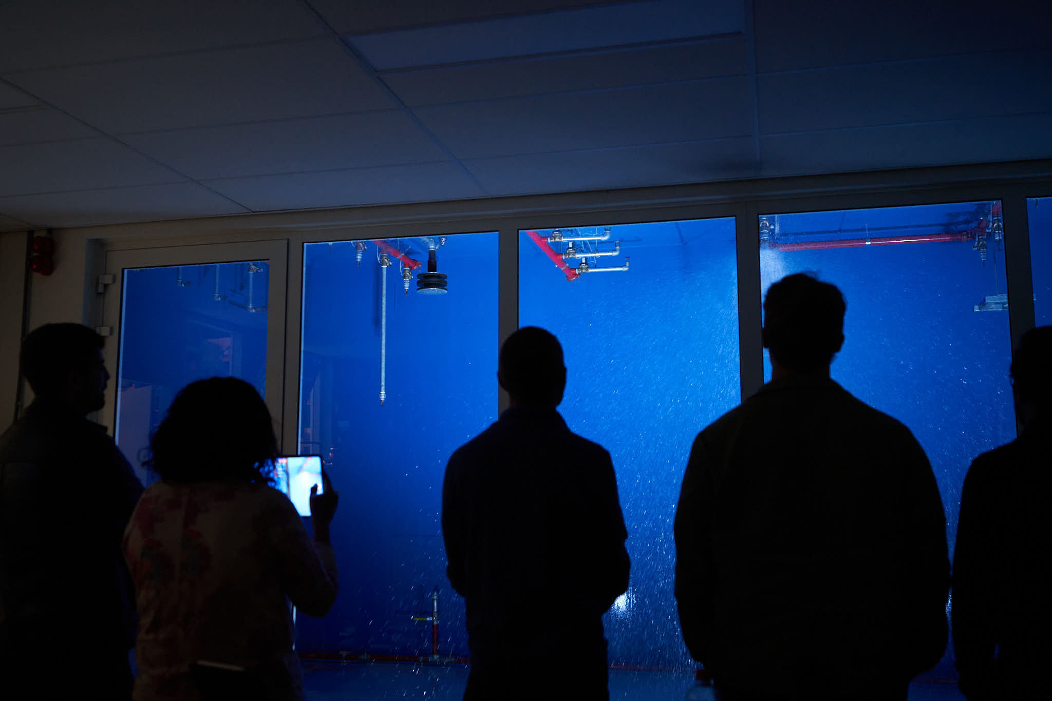 People observing water spray in test chamber.