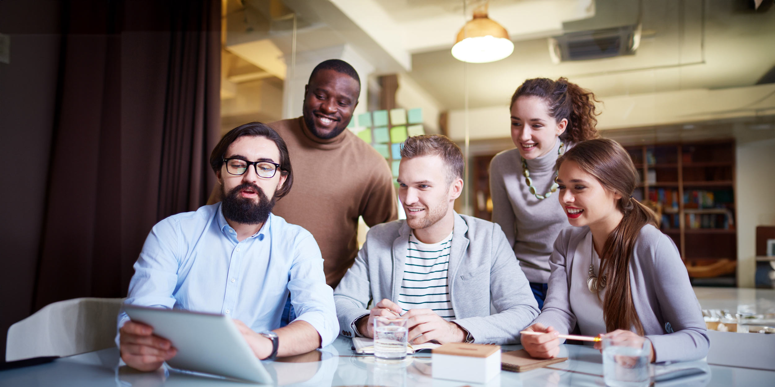 Young adult employees discussing with a touchpad during meeting