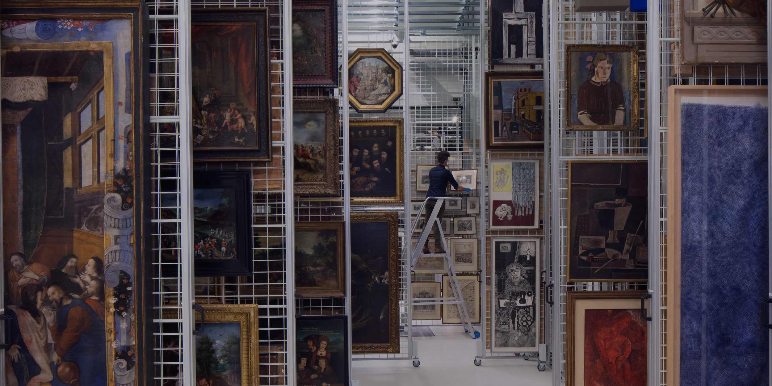 Person organizing paintings in an art storage facility.