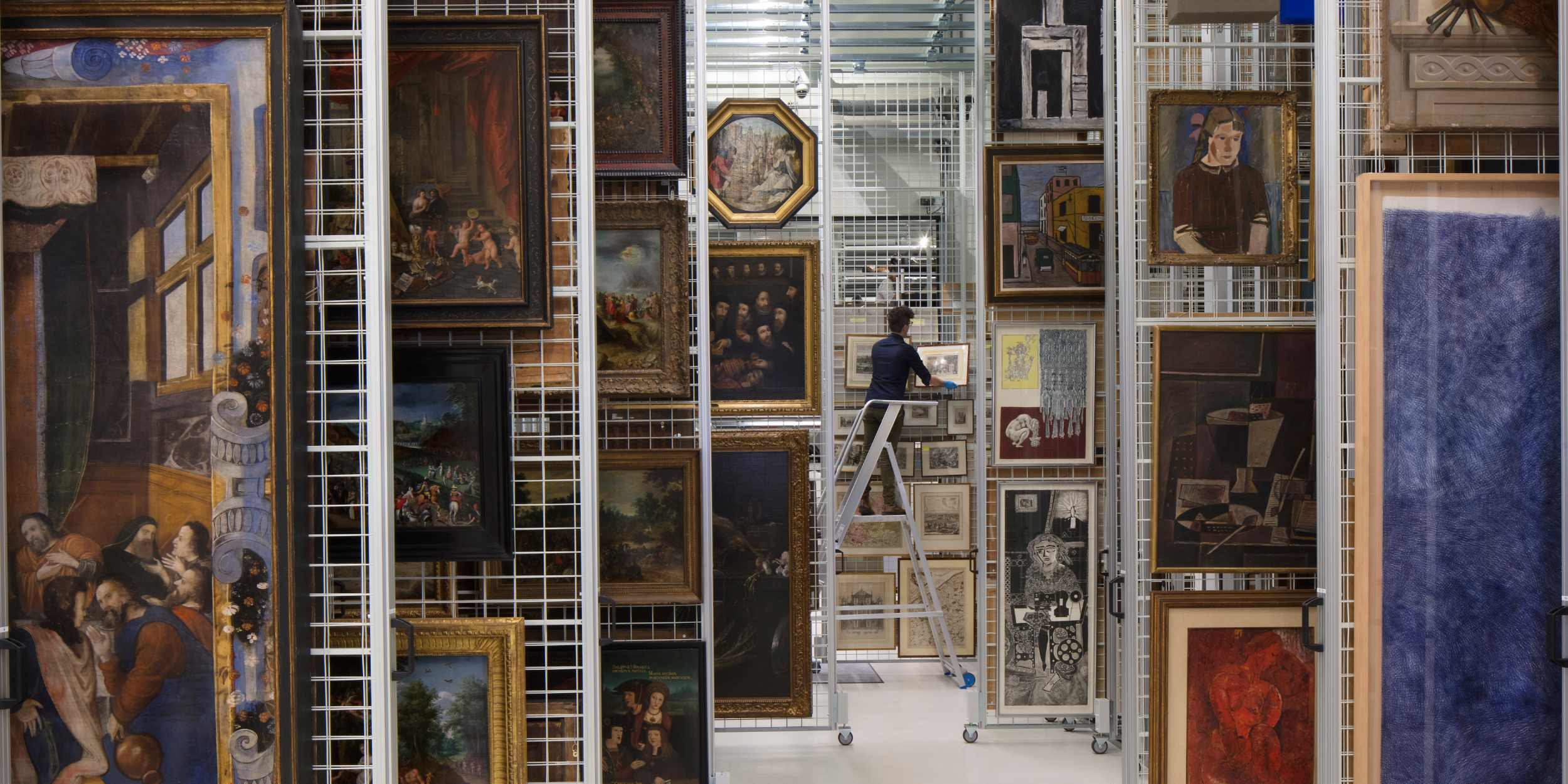 Person organizing paintings in an art storage facility.