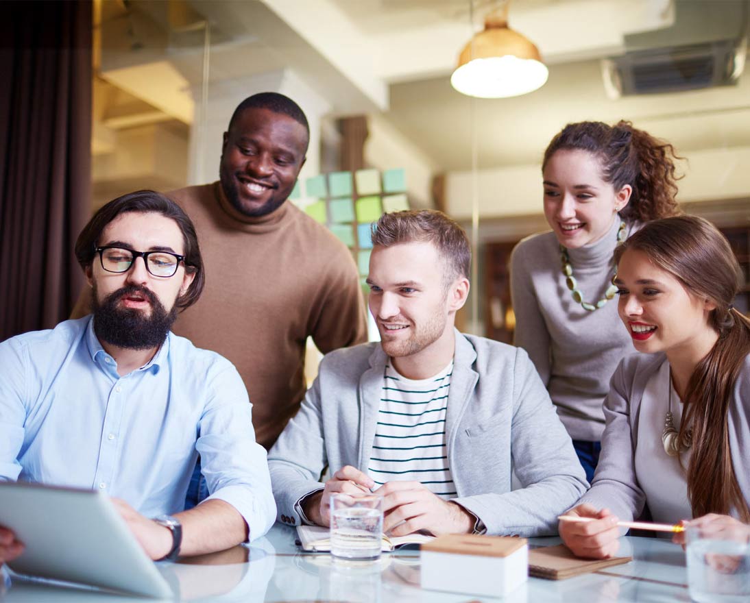 Young adult employees discussing with a touchpad during meeting