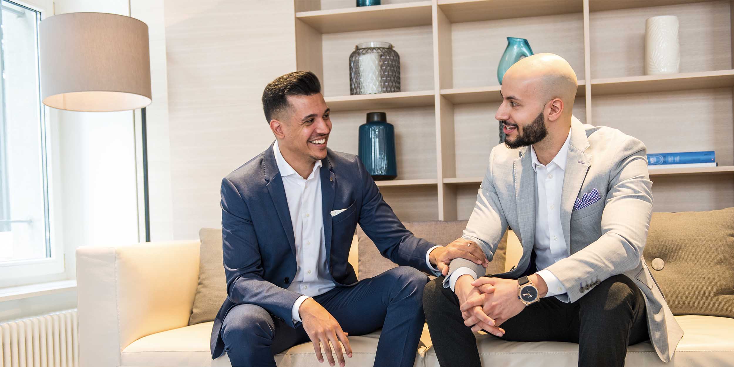 two men having a conversation on a couch