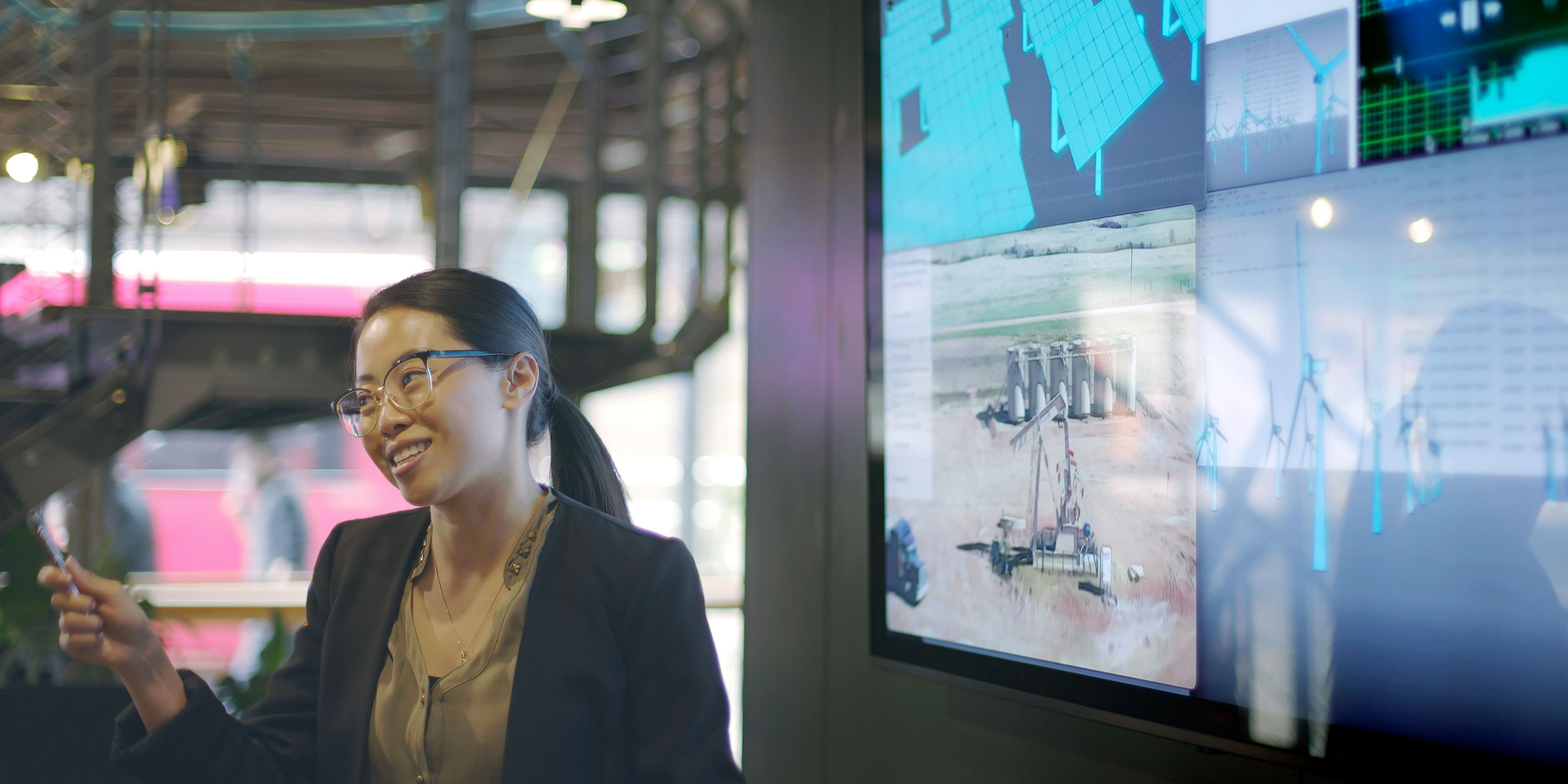 young Asian woman conducting a meeting with the aid of a large screen
