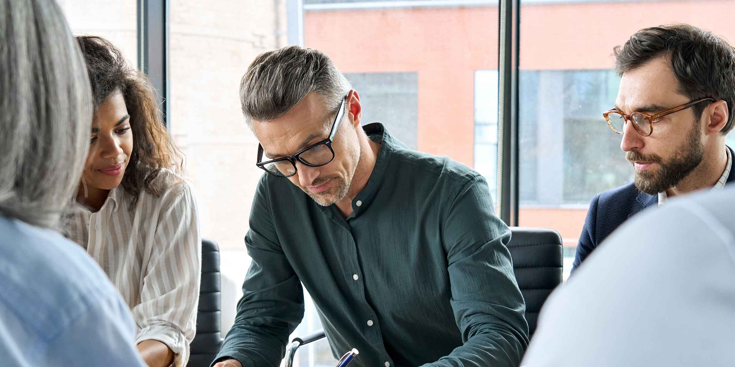 Businessman signing partnership contract at group meeting with partners