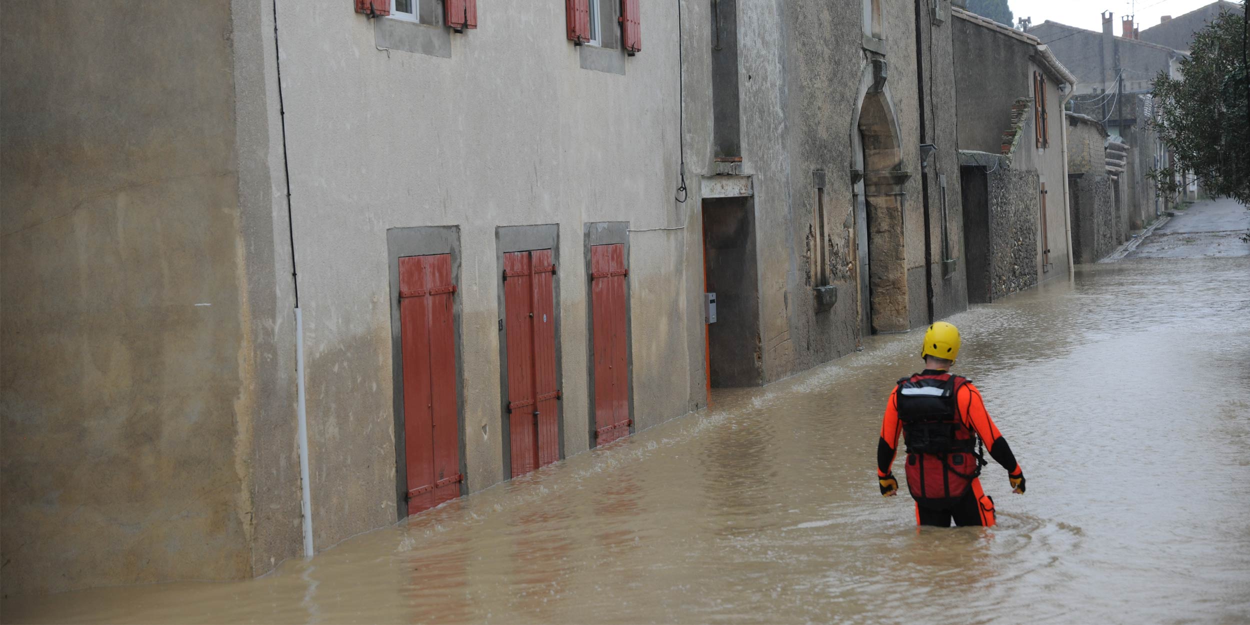 Rescuer walking through flooded street.