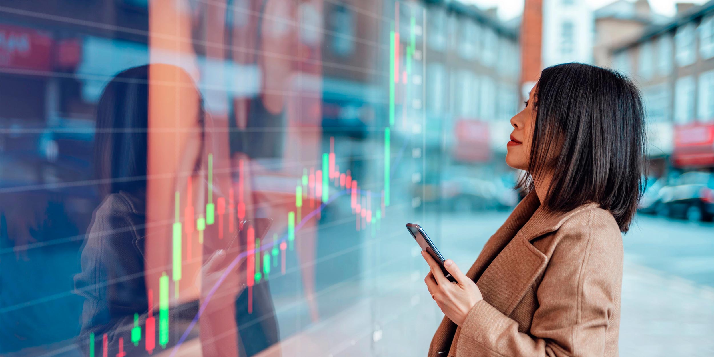 Woman looking at stock market screen while holding phone