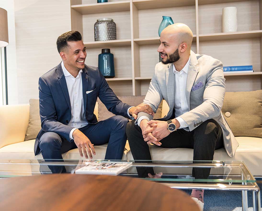 two men having a conversation on a couch