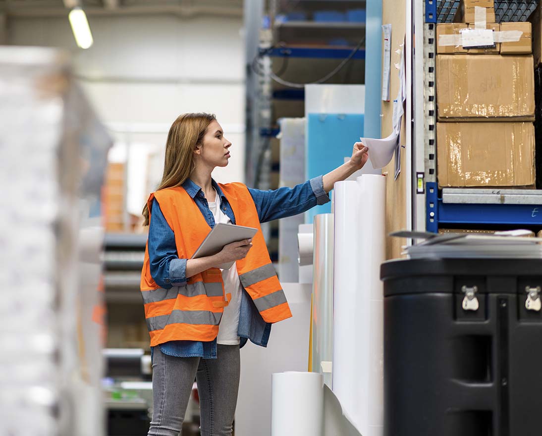 Woman with tablet in factory storehouse checking location of goods