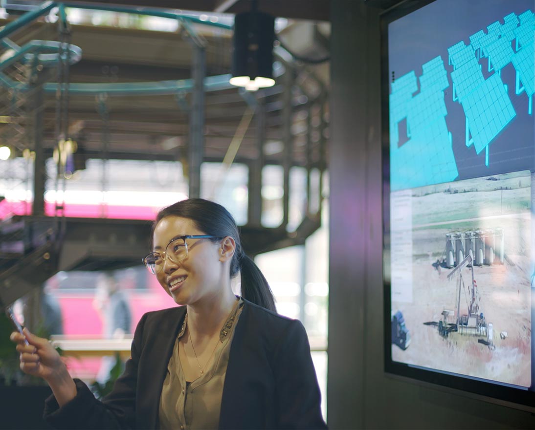 young Asian woman conducting a meeting with the aid of a large screen