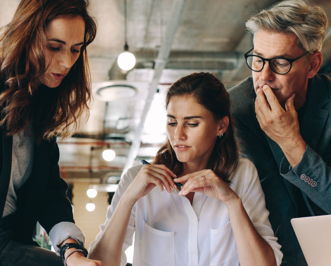 Three colleagues discussing work in a modern office.