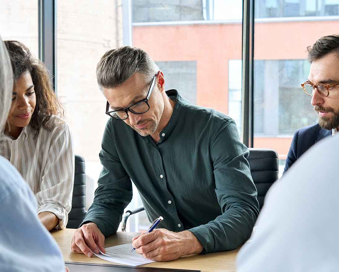 Businessman signing partnership contract at group meeting with partners