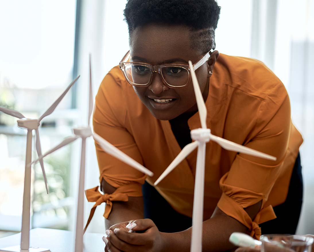 Woman wearing eyeglasses examining wind turbine models at office