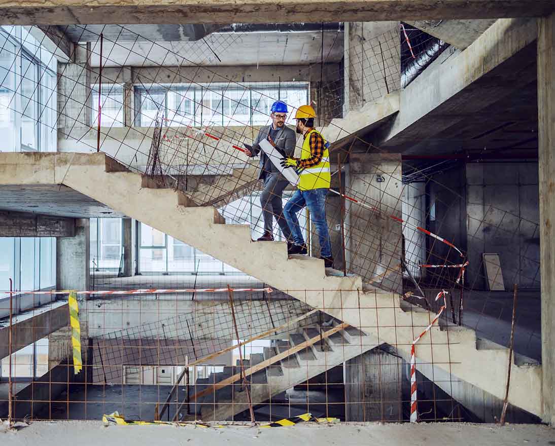 Construction worker and main architect climbing the stairs and talking about progress
