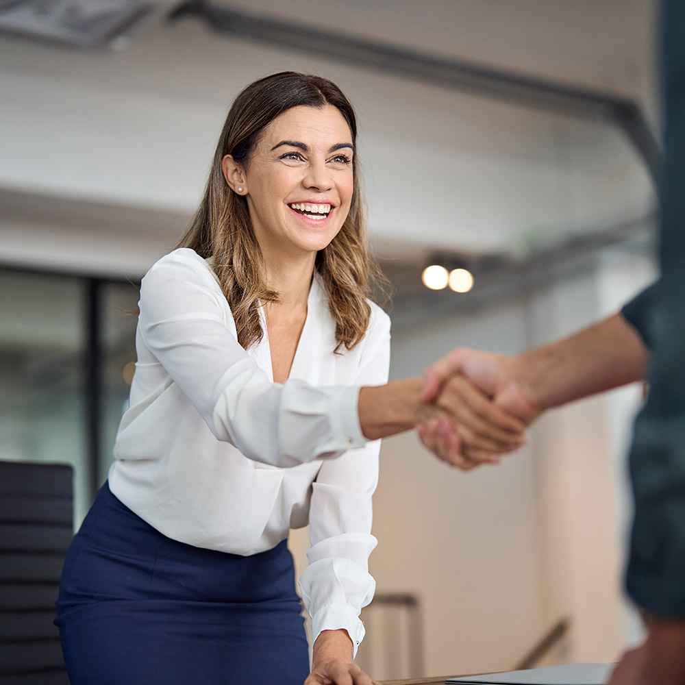 Happy business woman manager handshaking greeting client in office