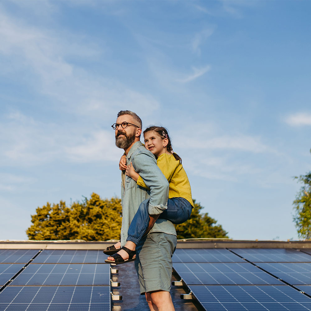 Father with girl on roof with solar panels
