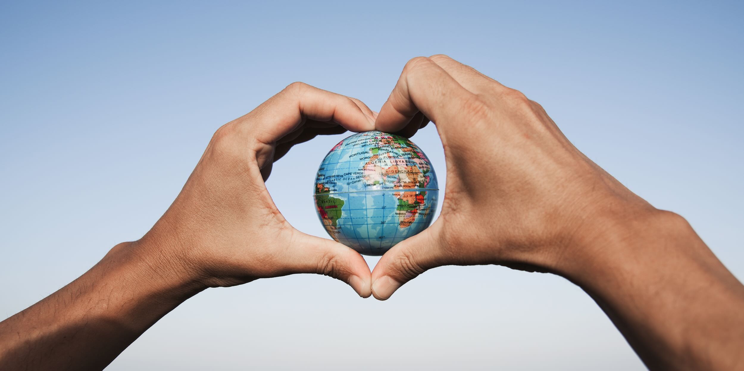 Small globe being held between hands in heart shape