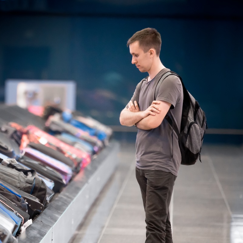 Man waiting at conveyor belt to pick his luggage
