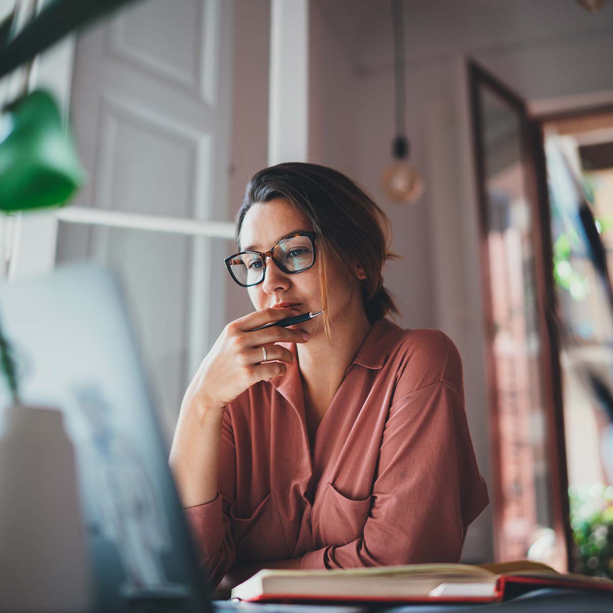 Young businesswoman thinking about something while sitting front open portable laptop computer