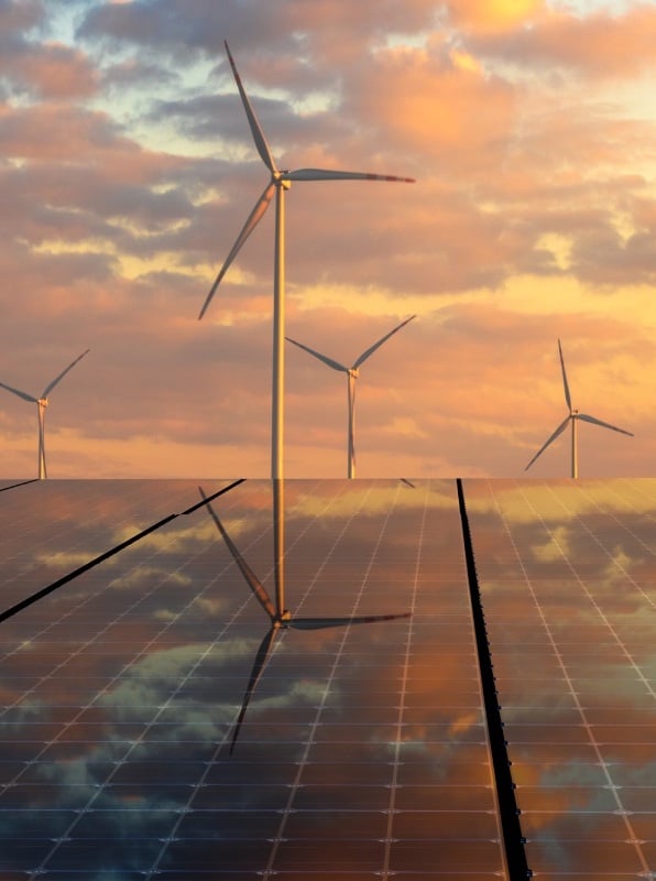 Wind turbines and solar panels at sunset sky.