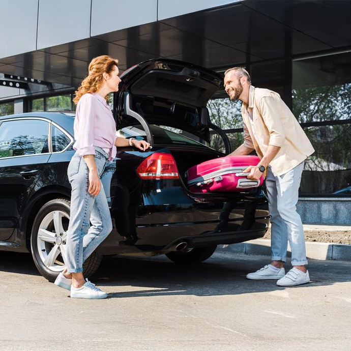 Couple loading suitcase into rental car