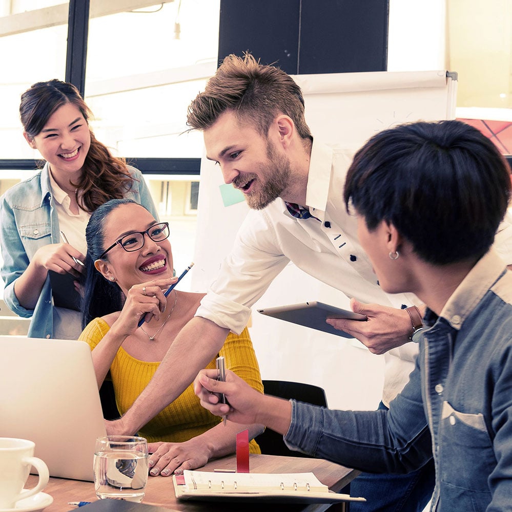 4-people-laughing-sitting-around-desk_1000x1000