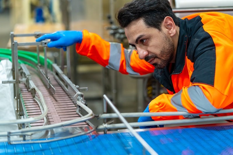Worker inspecting conveyor belt machinery